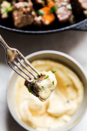 Steak bite on a fork dipped into curry aioli.