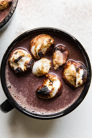 black mug of spiked hot chocolate topped with toasted marshmallows