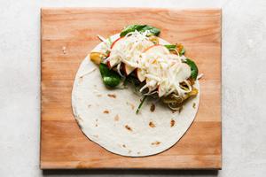 apples fontina cheese spinach and caramelized onions on a tortilla on a cutting board.