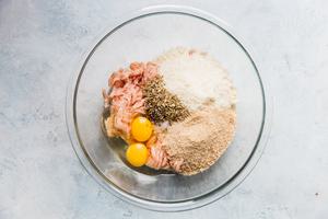 raw ingredients for baked chicken meatballs in a large glass bowl