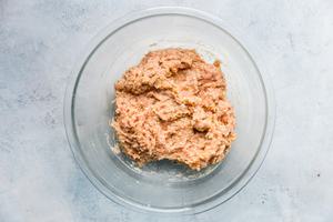 raw ingredients for Italian meatballs mixed together in a glass bowl