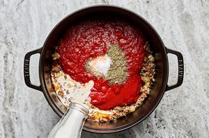 marinara, crushed tomatoes, salt, Italian seasoning, and cream being added to a pot with italian sausage, onion and garlic