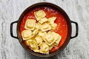 fresh cheese ravioli added to a a pot of sauce made with marinara, ground italian sausage and spices