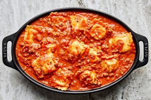 cheese ravioli in ground Italian Sausage marinara sauce in a baking dish