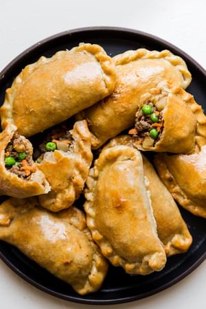 eight beef empanadas piled onto a black plate