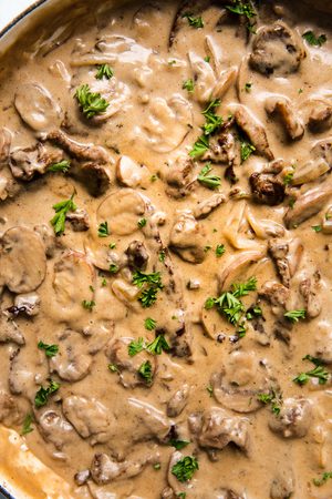 homemade beef stroganoff in a skillet sprinkled with fresh parsley, the perfect fall or winter dinner