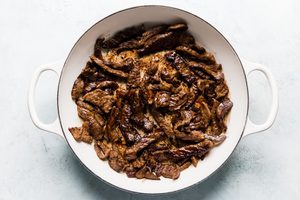 steak strips seasoned with salt being cooked in olive oil in a skillet to use for homemade beef stroganoff