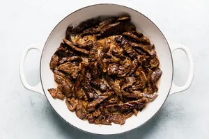 steak strips seasoned with salt being cooked in olive oil in a skillet to use for homemade beef stroganoff