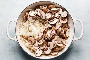 onions and mushrooms being cooked in butter in a skillet to be used as a base in beef stroganoff