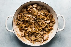 onions, mushrooms and garlic being cooked in butter in a skillet to use as a base in beef stroganoff