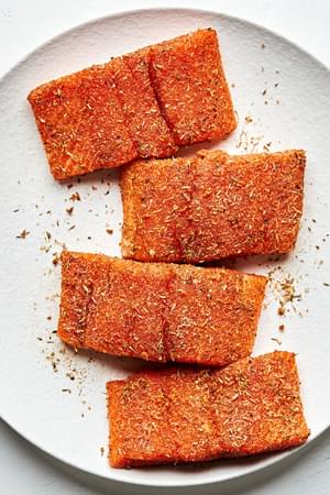 a plate of salmon rubbed with olive oil, brown sugar, paprika, garlic & onion powder, oregano, thyme, ginger, salt & cayenne