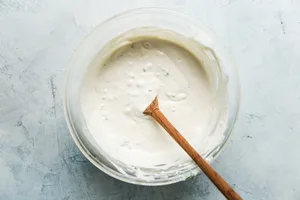 blue cheese dressing being stirred in a glass bowl