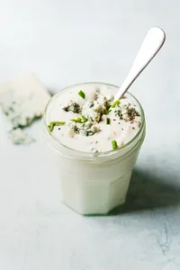 Homemade blue cheese dressing in a jar with a spoon.