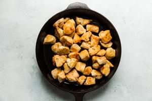 bite size chicken pieces browning in olive oil in a cast iron skillet