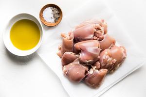 raw Boneless Skinless Chicken Thighs on parchment salt pepper in a bowl olive oil in bowl