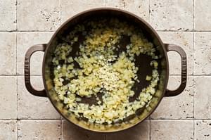 onions and garlic being cooked in olive oil in a large pot for making Brunswick Stew