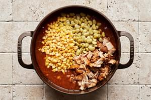 corn and lima beans being added to a pot with the remaining ingredients for Brunswick Stew
