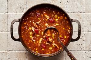 a pot of homemade Brunswick Stew with a ladle scooping a serving out