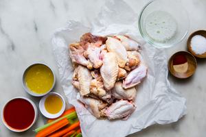 salt, garlic powder, paprika, chicken wingettes, egg whites, hot sauce, butter and honey in bowls on the counter