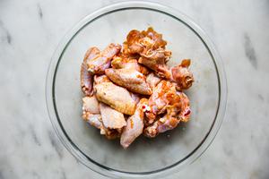 chicken wings tossed in salt, garlic powder and paprika in a glass bowl on the counter for baked buffalo wings
