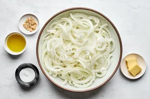 thinly sliced onions, butter, olive oil, salt and brown sugar laid out in bowls to make caramelized onions