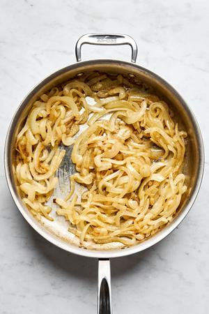 Onions slowly caramelizing in butter, oil, salt, and brown sugar, creating a rich, golden-hued medley of flavor.