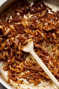 A close-up of golden-brown caramelized onions sizzling in a hot pan.