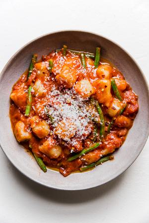 vodka sauce and green bean cauliflower gnocchi topped with fresh parmesan cheese in a bowl