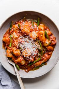 bowl of vodka sauce and green bean cauliflower gnocchi topped with parmesan cheese