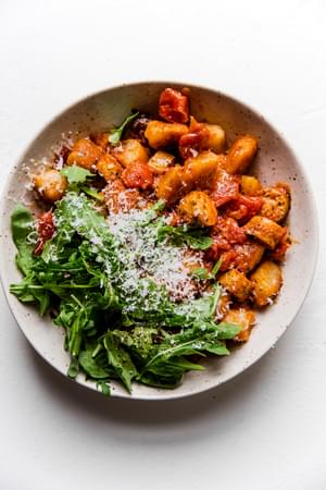 trader joe's cauliflower gnocchi with bruschetta sauce topped with fresh arugula
