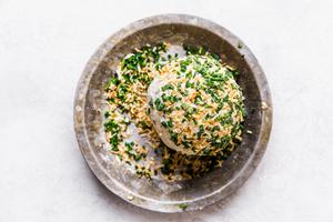 rolling cheddar cheese ball in chives and dried minced onions