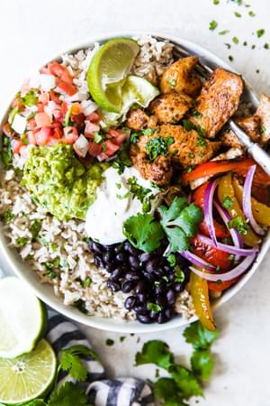 Chicken fajita Burrito Bowl with brown rice, black bean and taco chicken topped with guacamole and sour cream