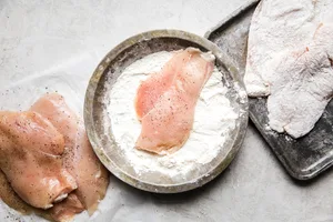 chicken breast cutlet dredged in flour and placed on a baking sheet