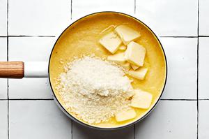 polenta, milk, chicken stock, butter and parmesan being cooked in a pot
