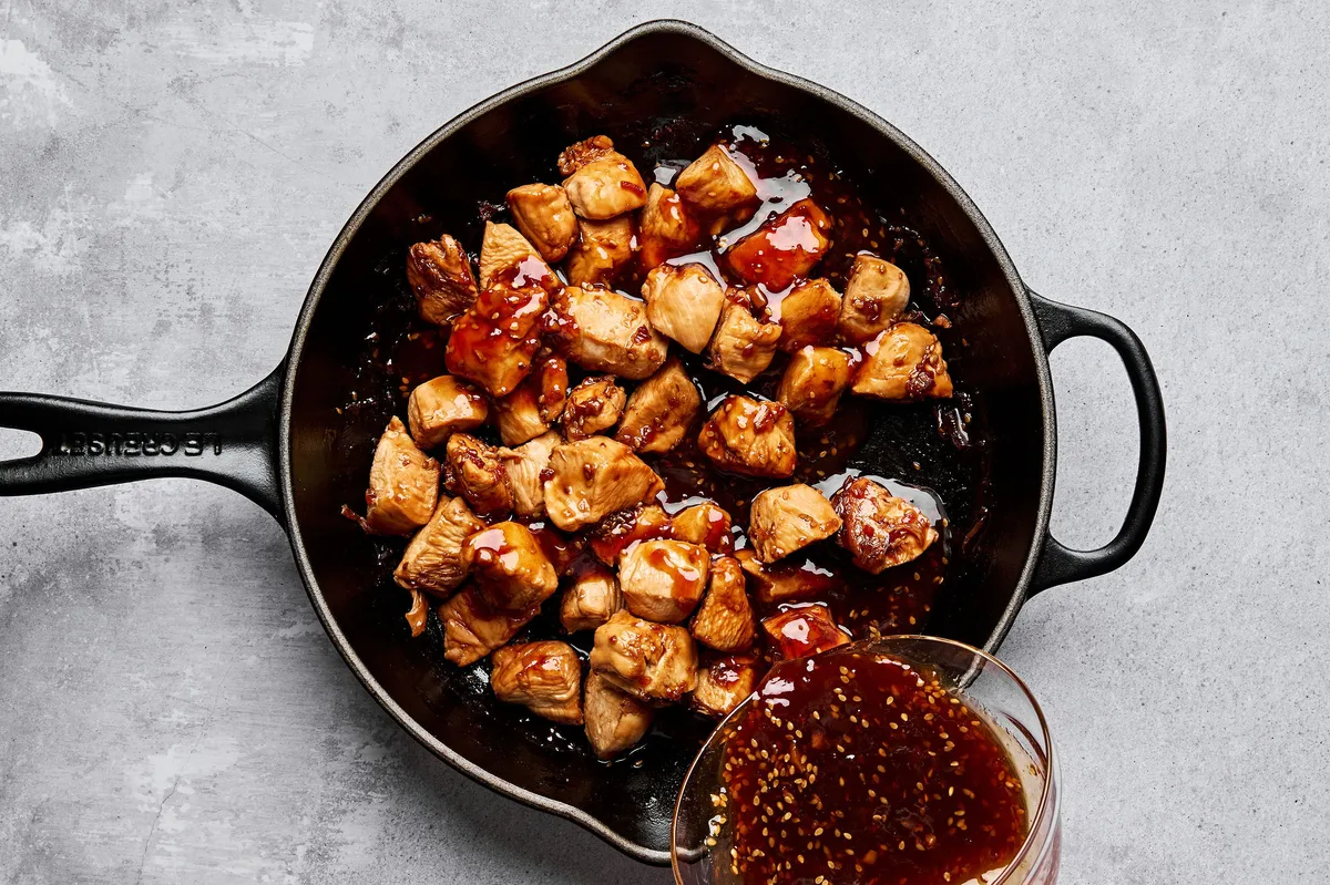 Teriyaki chicken cooking in a skillet until golden brown, with bubbling teriyaki sauce