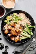Teriyaki chicken sushi bowl with sriracha mayo, cucumber, avocado and sesame seeds on a bed of seasoned brown rice