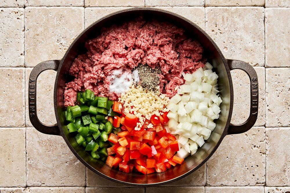 ground beef, onion, bell peppers, garlic, salt, and pepper being cooked in a soup pot