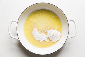 flour being added to melted butter in a white sauce pan