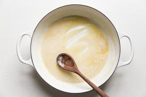 butter and flour being cooked to make a roux in a white sauce pan.