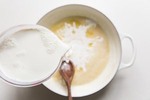 milk being added to butter and flour mixture.
