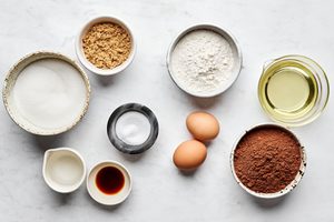 cocoa, flour, sugar, eggs, brown sugar, oil, vanilla and salt prepped and measured in bowls to make classic fudgy brownies