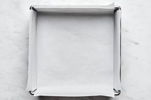 an 8x8 baking dish greased and lined with parchment paper for making classic fudgy brownies