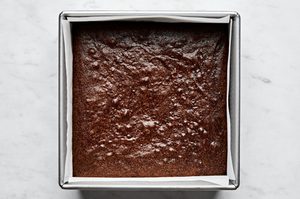 classic fudgy brownies in a parchment lined 8x8 pan fresh from the oven, warm and chocolatey
