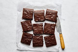 classic fudgy brownies sliced into 9 squares o a pice of parchment paper, the ultimate chocolatey dessert