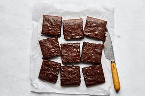 classic fudgy brownies sliced into 9 squares o a pice of parchment paper, the ultimate chocolatey dessert