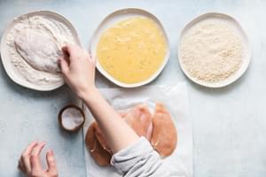 raw chicken being dipped in flour after being salted for crispy panko chicken