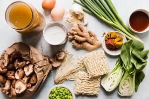 ingredients laid out broth, eggs, green onions, ramen noodles, coconut milk, red curry, bok choy, edamame