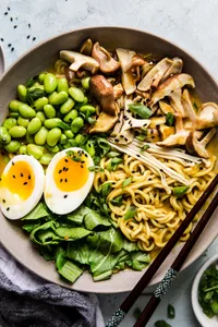 Bowl of vegetarian coconut curry ramen with mushrooms, bok choy, edamame and soft boiled egg with chopsticks