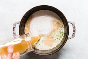 pouring broth and coconut milk into curry ramen soup