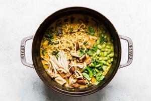 Pot of vegetarian coconut curry ramen with mushrooms, bok choy, edamame